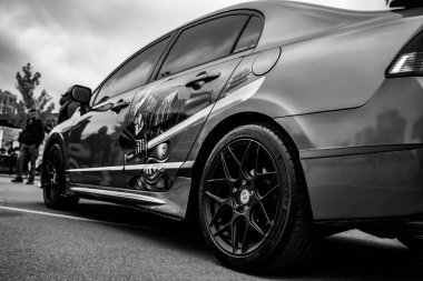 Aracın pürüzsüz gövdesi, gri tonda bile görülebilen kabartmalı grafiklerle süslenmiş ve özelleştirilmiş görünümünü ön plana çıkaran ayrıntılı kaportayla..