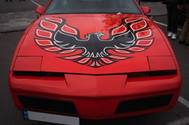 Kaputunu kaplayan siyah ve kırmızı bir Anka Kuşu 'na sahip canlı kırmızı bir araba..