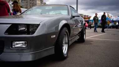 Arka planda insanların olduğu bir araba fuarında park edilmiş klasik bir kaslı araba..