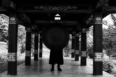 Parkta siyah elbisesi ve şapkası olan genç bir adam.