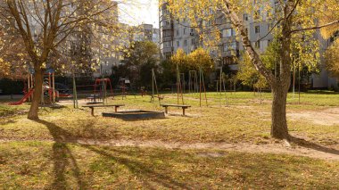 Sonbahar ağaçları ve düşen yapraklarla çevrili boş bir bahçedeki çocuk parkı..