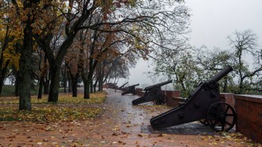 Tarihi bir parkta yağmurlu bir sonbahar gününde antik toplar. Yol dökülen yapraklarla kaplı ve melankolik atmosfere katkı sağlıyor..