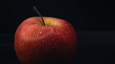 Sağlıklı beslenme kavramları için ideal siyah bir zemine karşı ıslak bir elmanın makro çekimi..