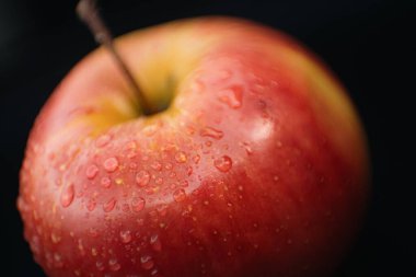 Kırmızı bir elmanın yüzeyindeki su damlacıklarının detaylı makro görüntüsü doğal tazeliği gösteriyor..