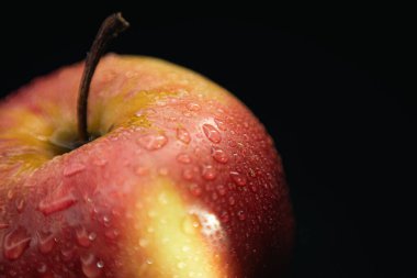 Sağlıklı beslenme kavramları için ideal siyah bir zemine karşı ıslak bir elmanın makro çekimi..