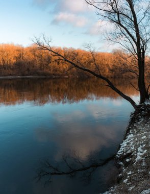 Nehir kıyısında kış dinginliği, altın renkleri ve huzurlu bir atmosferi var..