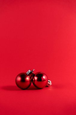 Kırmızı arka planda iki parlak kırmızı Noel mücevherinin minimalist fotoğrafı..