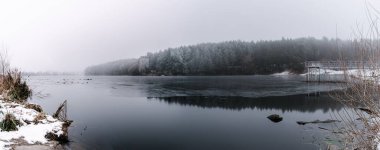 Sisli bir günde ormanla kaplı bir nehrin dikey görüntüsü.