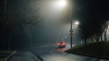 Islak asfalt ile sessiz gece yol sahnesi yoğun bir sis altında sokak lambaları yansıtan, kentsel ya da siyah-esinlenilmiş görseller için mükemmel.