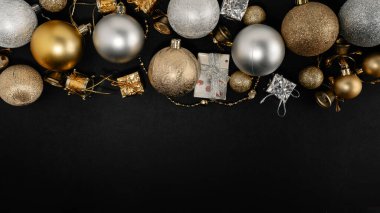 Siyah arka planda altın ve gümüş süslerle süslenmiş zarif bir Noel kompozisyonu, şenlikli ve lüks bir tatil atmosferi yaratıyor..