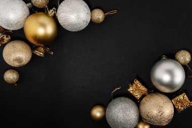 Siyah arka planda altın ve gümüş süslerle süslenmiş zarif bir Noel kompozisyonu, şenlikli ve lüks bir tatil atmosferi yaratıyor..