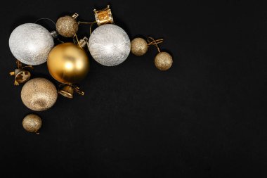 Siyah arka planda altın ve gümüş süslerle süslenmiş zarif bir Noel kompozisyonu, şenlikli ve lüks bir tatil atmosferi yaratıyor..