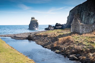  Burn of Latheronwheel, Caithness, Scotland. The Burn of Latheronwheel flows into the sea past the ruins of an abandoned croft, In the middle there is a rocky outcrop in the sea reaching up into a blue sky. clipart