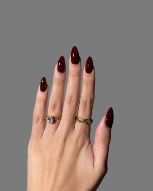 Hands and fingers of young woman with colorful and modern nail polish manicure with gold rings on her fingers with gray background  clipart