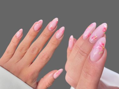 Renkli ve süslü manikürlü modern moda yaratıcı şekilleri ve gri arkaplan çizimleri olan genç bir kadının elleri ve parmakları. 