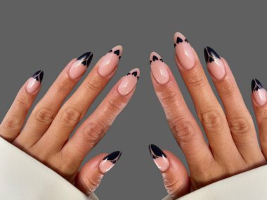 Renkli ve süslü manikürlü modern moda yaratıcı şekilleri ve gri arkaplan çizimleri olan genç bir kadının elleri ve parmakları. 