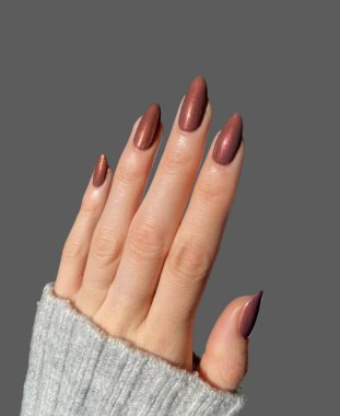 Renkli ve süslü manikürlü modern moda yaratıcı şekilleri ve gri arkaplan çizimleri olan genç bir kadının elleri ve parmakları. 