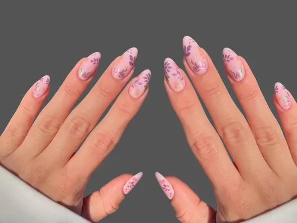 Renkli ve süslü manikürlü modern moda yaratıcı şekilleri ve gri arkaplan çizimleri olan genç bir kadının elleri ve parmakları. 