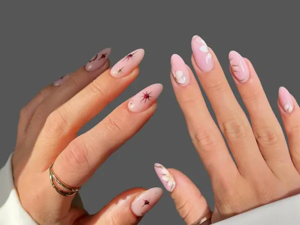 Renkli ve süslü manikürlü modern moda yaratıcı şekilleri ve gri arkaplan çizimleri olan genç bir kadının elleri ve parmakları. 
