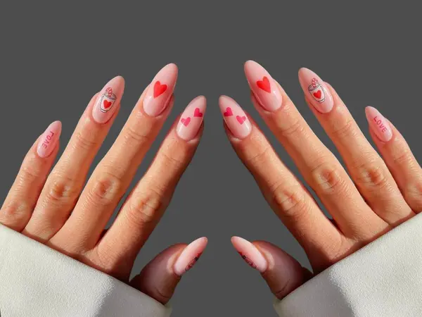 Renkli ve süslü manikürlü modern moda yaratıcı şekilleri ve gri arkaplan çizimleri olan genç bir kadının elleri ve parmakları. 