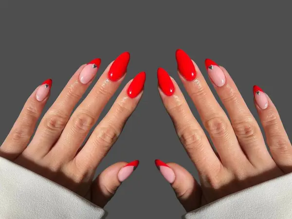 Renkli ve süslü manikürlü modern moda yaratıcı şekilleri ve gri arkaplan çizimleri olan genç bir kadının elleri ve parmakları. 