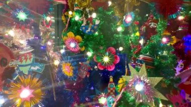 Bu canlı Noel ağacında renkli suni çiçekler ve ışıldayan yıldızlar var. Parlayan ışıklar ve parlayan ampullerle güzelce süslenmiş. Bayram kutlamaları için mükemmel bir ortam yaratıyor..