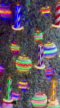 Renkli mumlardan ve parlak ip ışıklarıyla süslenmiş şenlikli kurdelelerden oluşan canlı bir düzenleme. Noel dekorasyonu veya neşeli yeni yıl kampanyaları için ideal.