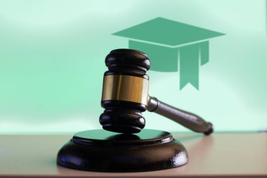 Arka planda mezuniyet şapkası ikonu olan tahta bir tokmak eğitim ve hukuku simgeliyor..