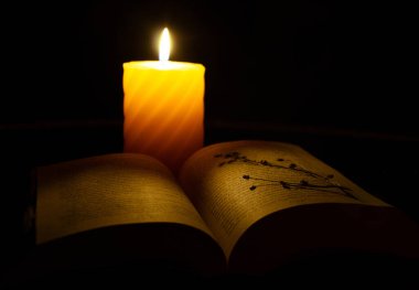 open book near candle at night clipart