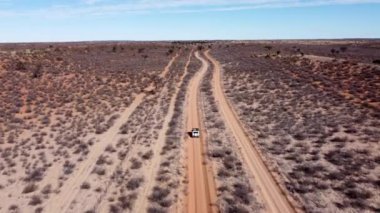 İnsansız hava aracı, Kalahari Çölü 'nün uçsuz bucaksız boşluğundan geçen küçük bir arabanın arkasında uçuyor. Kalahari Namibya D1022. Muhteşem Kalahari yolları