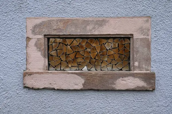 Kışın kuruması için eski bir çiftlik evinin bodrum penceresine istiflenmiş ahşap kılıf.