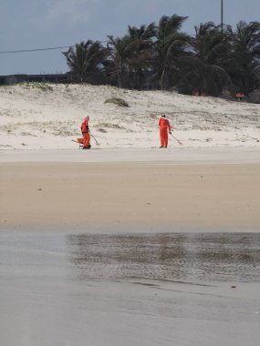 Employees of a state-owned company, properly uniformed, working on cleaning the beach   clipart