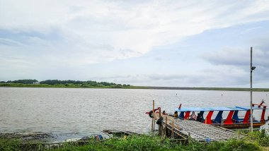 Suda teknesi olan bir sahil. Gökyüzü bulutlu ve su sakin.