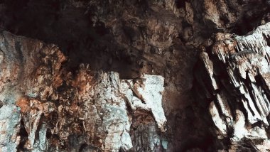 Üzerinde yeşil bitkiler büyüyen kayalık bir uçurum. Bitkiler uçurumun kenarında yetişiyor ve uçurum yosunlarla kaplı. Huzurlu ve huzurlu bir sahne.