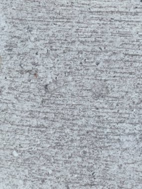 Birkaç renk lekesi olan gri ve beyaz bir duvar. Duvar betondan yapılmış ve pürüzlü bir dokusu var.