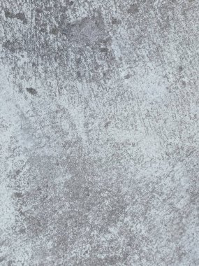 Birkaç renk lekesi olan gri ve beyaz bir duvar. Duvar betondan yapılmış ve pürüzlü bir dokusu var.