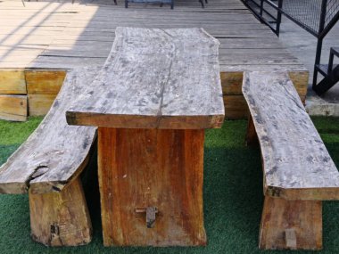 Kırsal bir ahşap masa ve tezgahlar açık bir verandaya kurulmuş, doğal, el yapımı tasarımlar sergileniyor. Toplanma için ideal, rahat ve organik bir atmosfer yaratmak için..