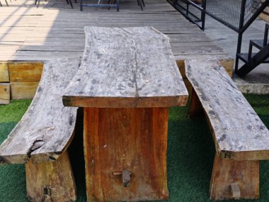 Kırsal bir ahşap masa ve tezgahlar açık bir verandaya kurulmuş, doğal, el yapımı tasarımlar sergileniyor. Toplanma için ideal, rahat ve organik bir atmosfer yaratmak için..