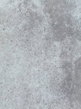 Birkaç renk lekesi olan gri ve beyaz bir duvar. Duvar betondan yapılmış ve pürüzlü bir dokusu var.