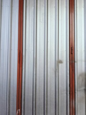 Kırmızı süslemeli, endüstriyel tasarım ve dokusunu ön plana çıkaran kıvrımlı metal duvarın yakın çekim görüntüsü. Metalik parıltı kırmızımsı tonla çelişiyor, modern ama kırsal bir his veriyor..