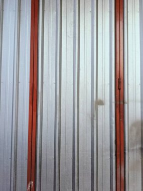 Kırmızı süslemeli, endüstriyel tasarım ve dokusunu ön plana çıkaran kıvrımlı metal duvarın yakın çekim görüntüsü. Metalik parıltı kırmızımsı tonla çelişiyor, modern ama kırsal bir his veriyor..