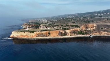 İnsansız hava aracı Vincente Point Deniz feneri manzaralı Abalone Koyu üzerindeki uçurumlara doğru uçuyor.