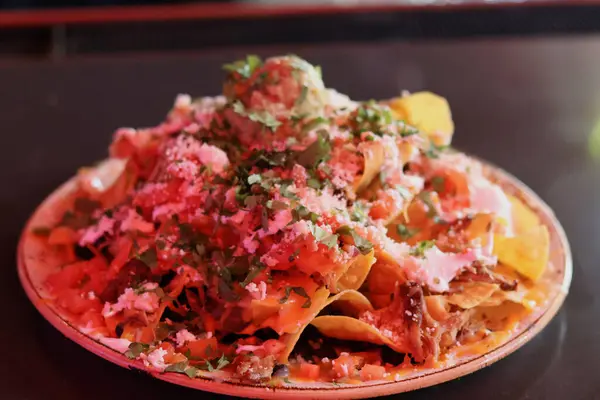 Guacamole, domates ve salsa soslu nacho.