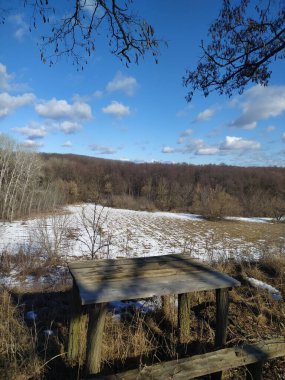Kış günü. Tepedeki masa ve bank. Kış orman manzarası.