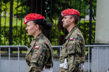 Warsaw, Poland - August 15 2014: two Polish soldiers, a man and a woman, wearing red berets marching during the celebration of the Armed Forces Day clipart