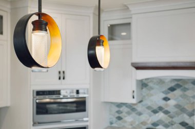 Bir çift modern mutfak kolyesi sarı ve siyah tonları ile, çarpıcı ve çağdaş bir tasarım elementi oluşturan parlak ve şık mutfak alanı.