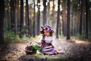 Bu ormandaki güzel bir kızın görüntüsü. O, yerde oturuyor. Yanında yaban mersini ve bitkilerle dolu bir sepet var. Kız güzel bir elbise ve şapka giymiş.