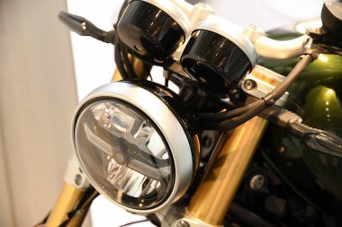Motosikletin ön tarafını kapatın. Merkezde krom çerçeveli yuvarlak bir far var..