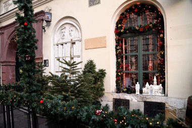 Noel süslemeleriyle süslenmiş güzel bir vitrin. Pencereler yeşil dallar ve parlak çelenklerle çerçevelenmiş..