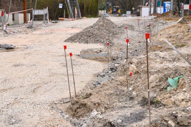 Toprak kazılmış, toprak ve moloz yığınları görülebiliyor. Önerilen rota boyunca kırmızı plastik uçlu ince metal çubuklar yerleştirildi.